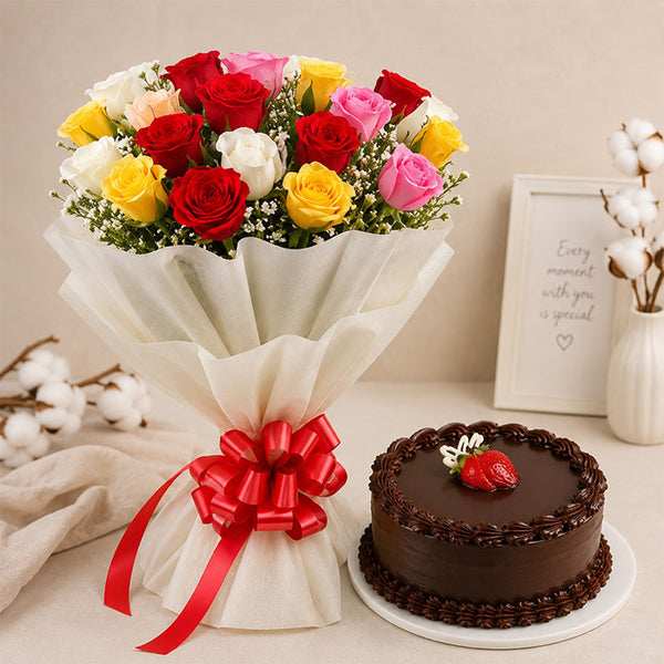 Bouquet of colorful roses with a red bow and a chocolate cake on a table.