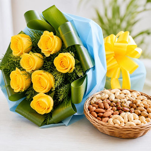 Bouquet of yellow roses with a bowl of mixed nuts on a light surface.