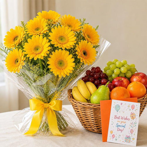 Bouquet of yellow flowers with a basket of fruits and a card on a light surface.