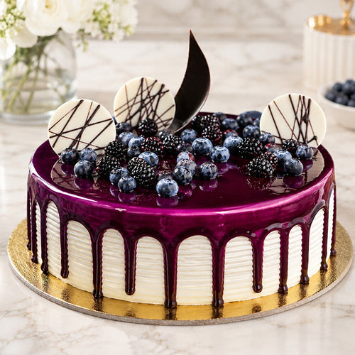 Decorative cake with purple glaze, berries, and white chocolate pieces on a marble surface.