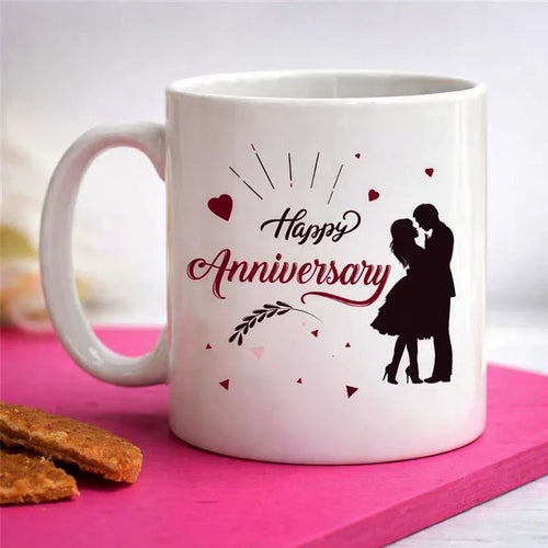 White mug with 'Happy Anniversary' design featuring a couple on a pink surface.