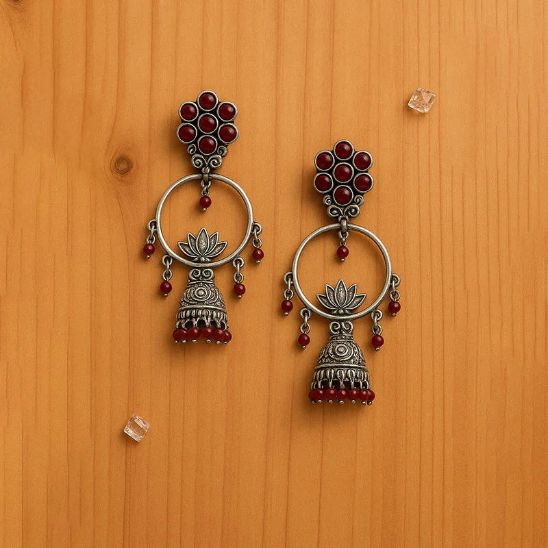 Pair of silver and red beaded earrings on a wooden surface