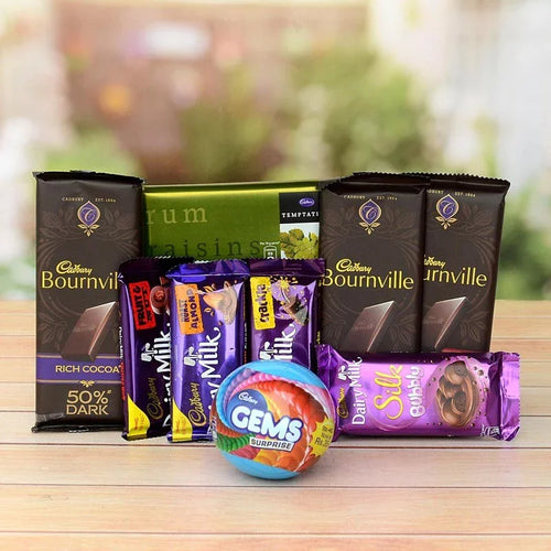 Assorted chocolate bars including Cadbury Bournville and Dairy Milk on a wooden surface with a blurred outdoor background.
