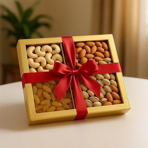 Assorted dry fruits gift box with cashews, almonds, raisins, and pistachios in gold packaging tied with a red ribbon.