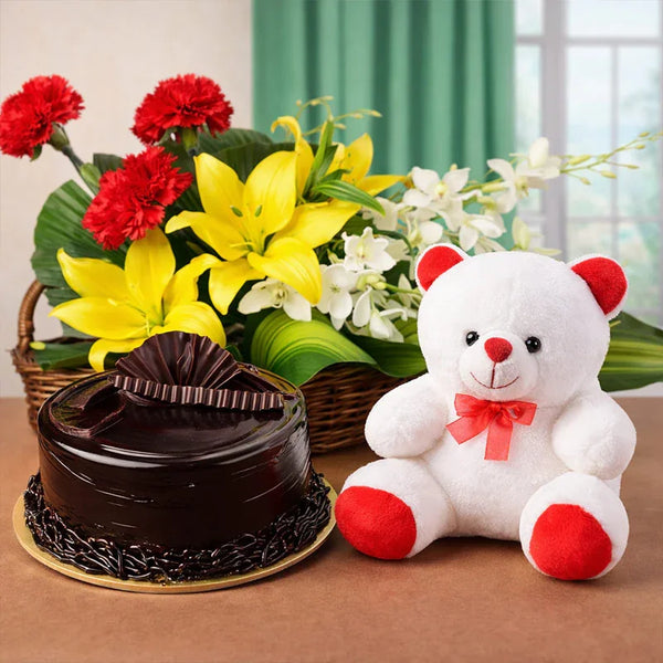 Gift basket with yellow lilies, red carnations, chocolate cake, and white teddy bear