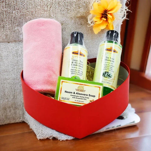Bathroom essentials including a towel, shampoo, conditioner, and soap in a red basket on a wooden surface.