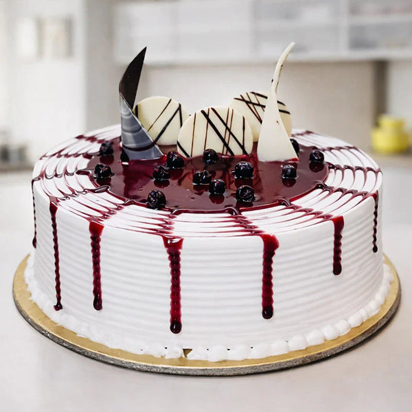 White cream cake with berry sauce, chocolate decorations, and whole berries on top