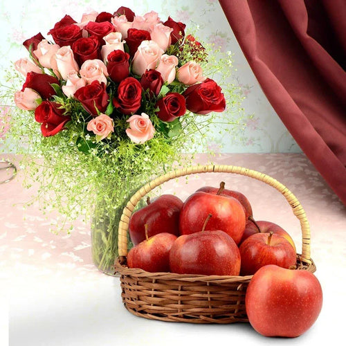 Basket of red apples with a bouquet of red and pink roses on a light background
