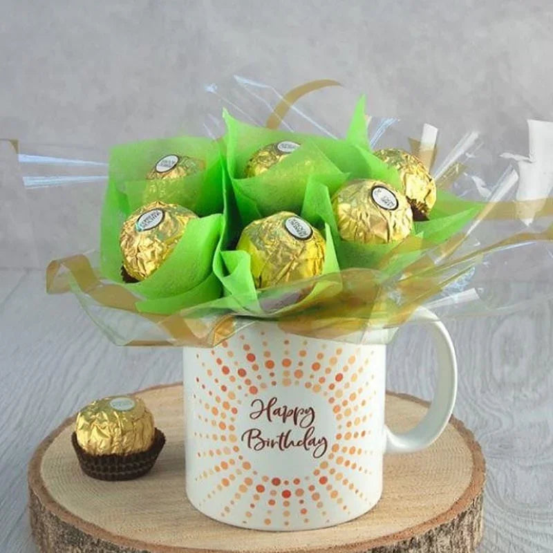 Bouquet of Ferrero Rocher chocolates in a 'Happy Birthday' mug on a wooden stand.