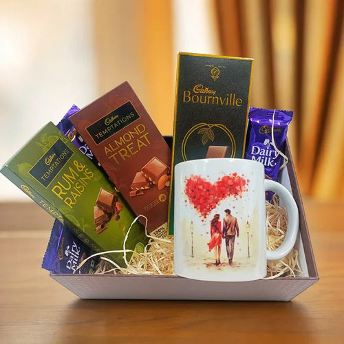 Gift basket with Cadbury chocolate bars and a mug on a wooden surface