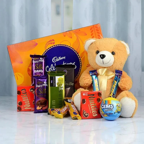 Assorted chocolates and a teddy bear on a reflective surface with a light gray curtain background
