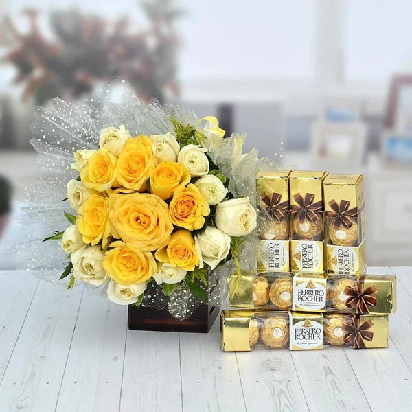 Bouquet of yellow and white roses with Ferrero Rocher chocolates on a light wooden surface.