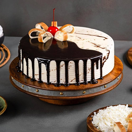 Chocolate vanilla cake with chocolate ganache drip, cherry, and white chocolate garnish 