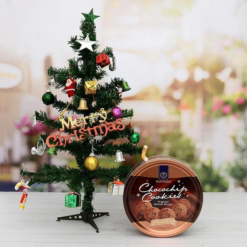 Decorated Christmas tree with ornaments and a container of cookies on a blurred background