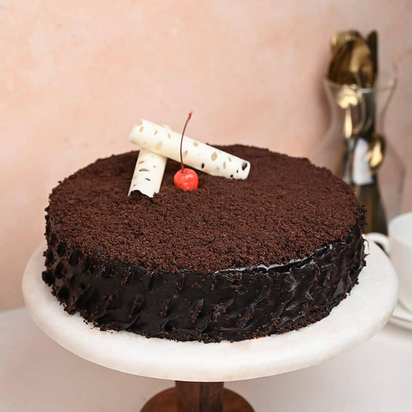 Chocolate mud cake on stand with cherry and white chocolate decoration