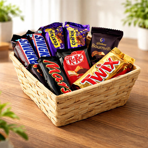 Basket of assorted chocolate bars including Mars, KitKat, and Twix on a wooden surface.