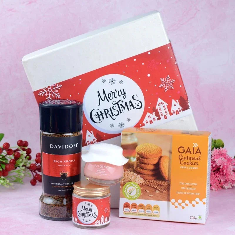 Christmas-themed gift set with coffee, cookies, and a box on a pink background