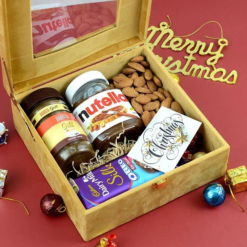 Gift box with Nutella, Lindt, and almonds on a red background with 'Merry Christmas' decoration.