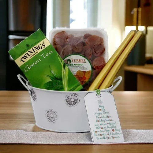 Gift basket with Twinings green tea, dried apricots, golden sticks, and greeting card on table