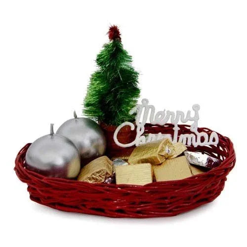 Christmas gift basket with chocolates, silver candles, small green tree, and 'Merry Christmas' sign