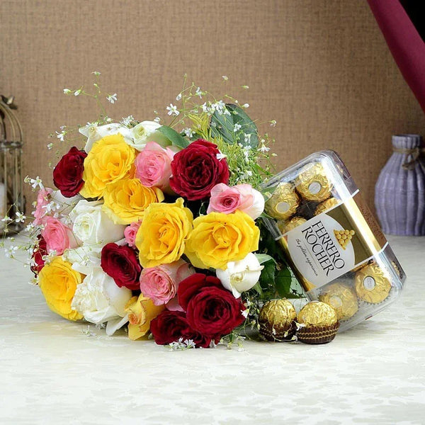 Bouquet of colorful roses with a box of Ferrero Rocher chocolates on a wooden surface.