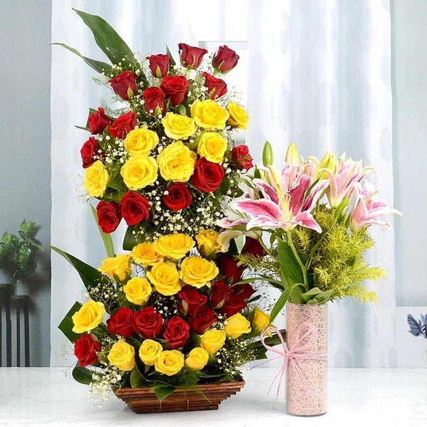 Floral arrangement with red and yellow roses and a smaller bouquet of pink lilies on a white background.