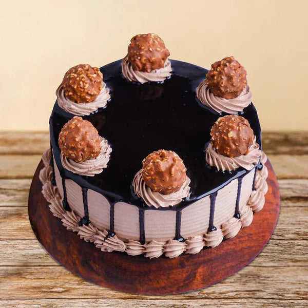 Decorative cake with chocolate ganache and Ferrero Rocher chocolates on a wooden surface