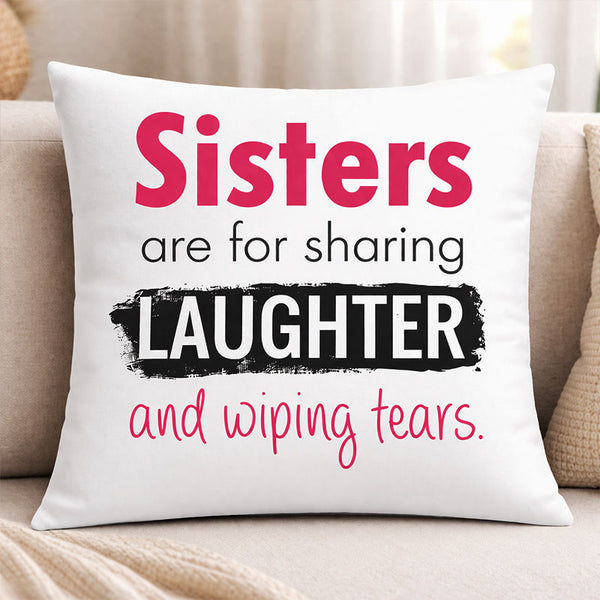 White pillow with text 'Sisters are for sharing laughter and wiping tears' on a beige couch.