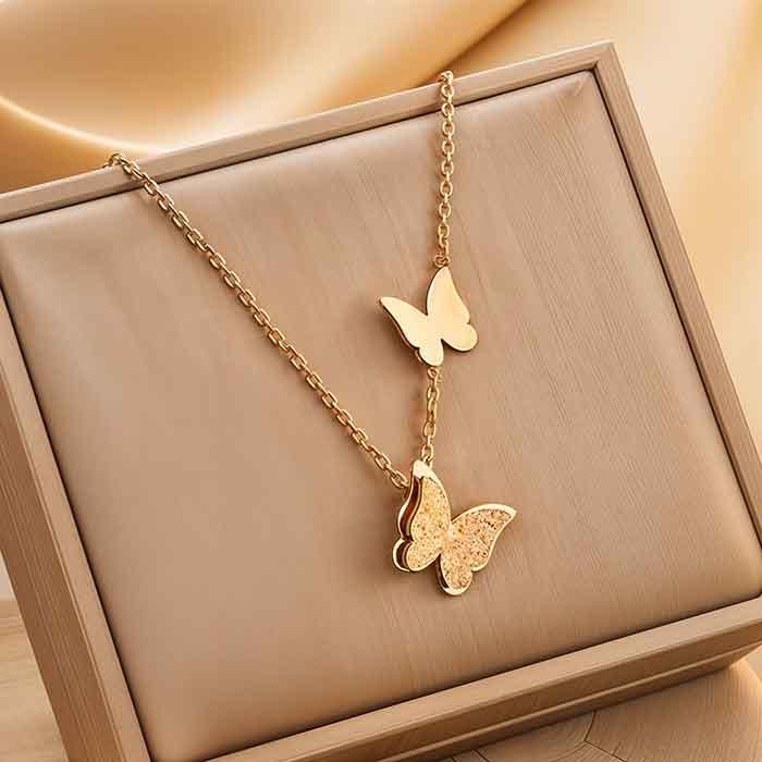 Gold butterfly necklace on a beige cushioned surface