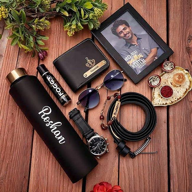 Collection of personal items including a water bottle, wallet, sunglasses, watch, and jewelry on a wooden surface.