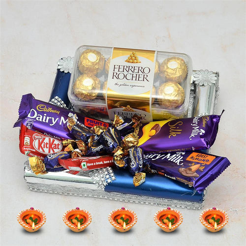 Assorted chocolate bars including Ferrero Rocher, Cadbury Dairy Milk, and KitKat in a decorative box on a light background.