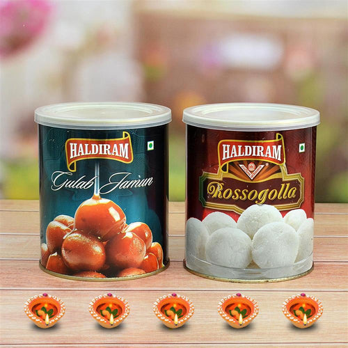 Two Haldiram tins, one with Gulab Jamun and the other with Rossogolla, on a wooden surface with a blurred background.