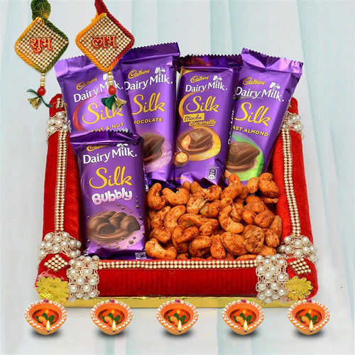 Dairy Milk Silk chocolate packets with nuts on a decorative tray against a light gray background