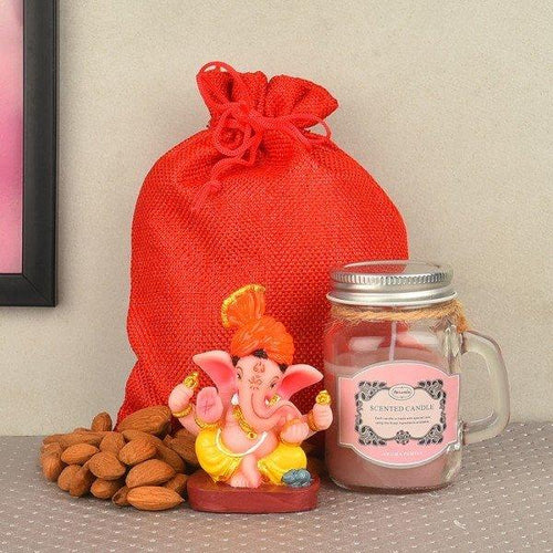 Decorative item with a red bag, Ganesha statue, and scented candle on a gray surface.