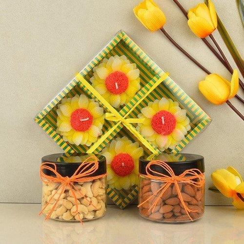 Sunflower-shaped candles in a decorative box with two jars of nuts on a light background.