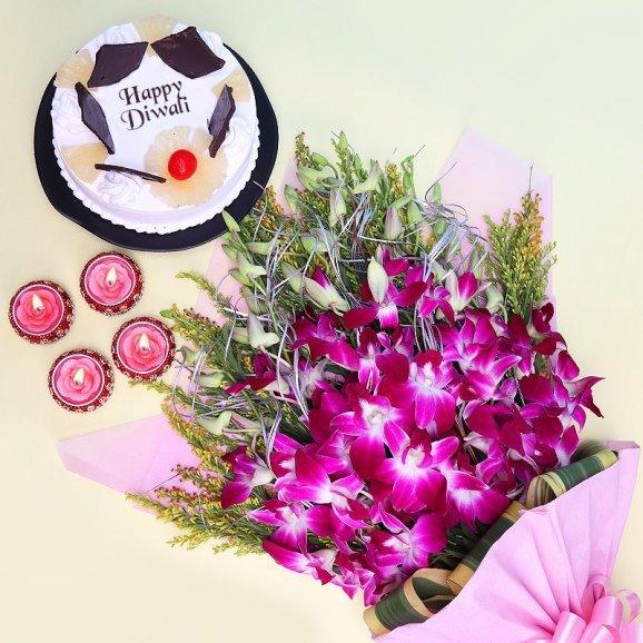 Bouquet of purple flowers with diya and a Diwali cake on a light green background