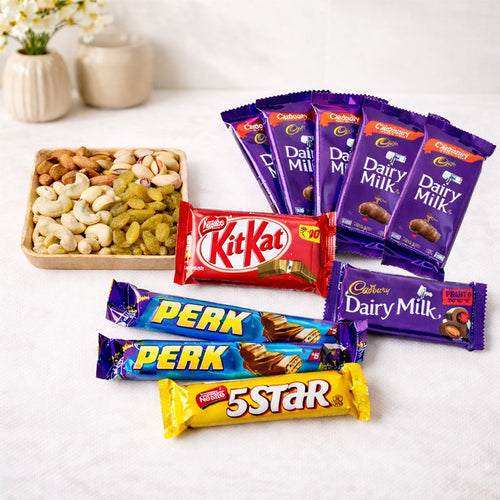 Assorted chocolate bars including Cadbury Dairy Milk, KitKat, and Perk on a white surface with a tray of nuts.