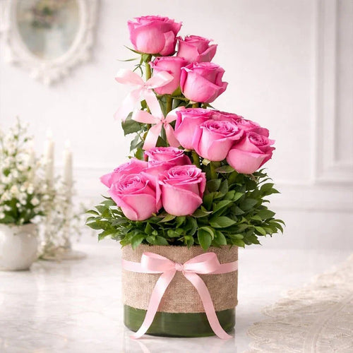 Bouquet of pink roses in a container with a pink ribbon on a light background