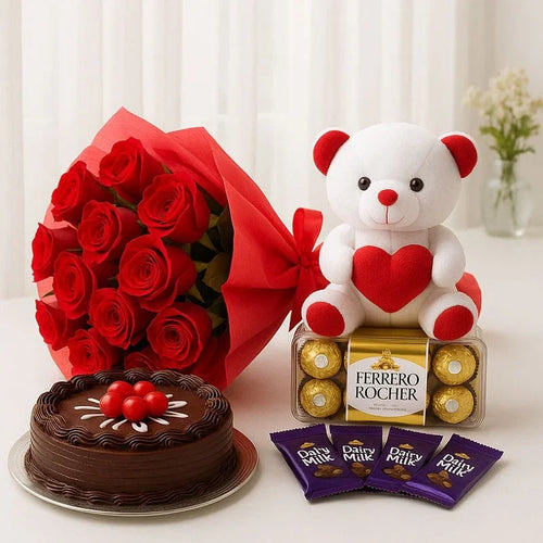 Bouquet of red roses, chocolate cake, teddy bear with heart, Ferrero Rocher chocolates, and Dairy Milk packets on a white surface.
