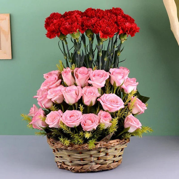 Basket of pink roses and red carnations on a green background