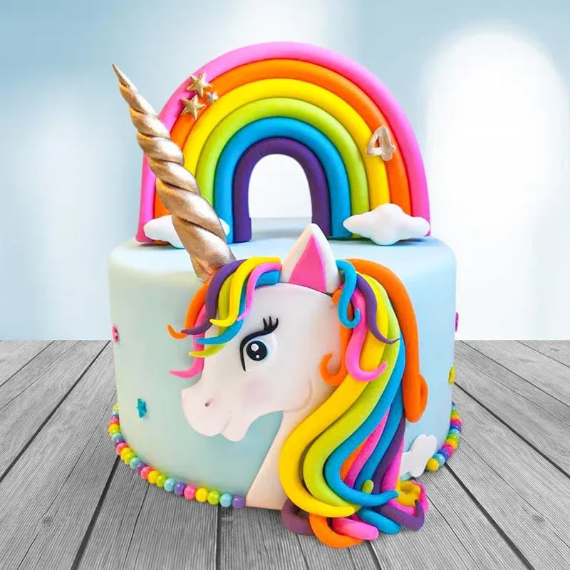 Unicorn cake with rainbow colors and a unicorn horn on a wooden surface.