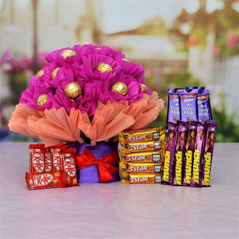Bouquet of pink flowers with chocolate eggs and a display of chocolate bars on a table.