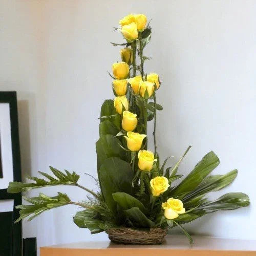 Elegant yellow rose flower arrangement in a basket with green leaves, perfect for gifting