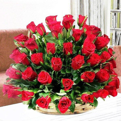 Bouquet of red roses in a woven basket on a white surface with a blurred background
