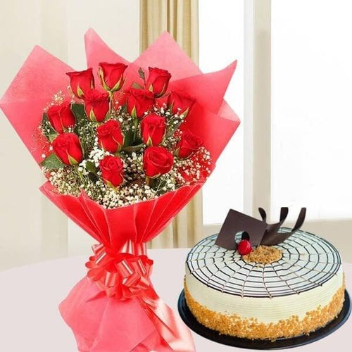 Bouquet of red roses wrapped in red paper and a cake with a spider web design on a white surface.
