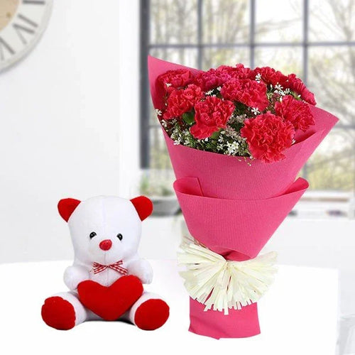 Bouquet of red flowers wrapped in pink paper with a white teddy bear holding a red heart on a light background.