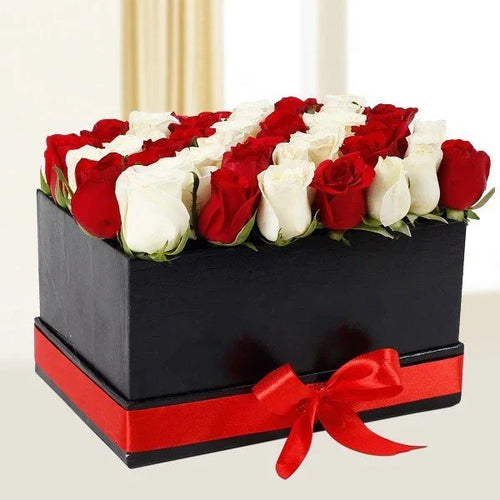 Black box with red and white roses and a red ribbon on a light background