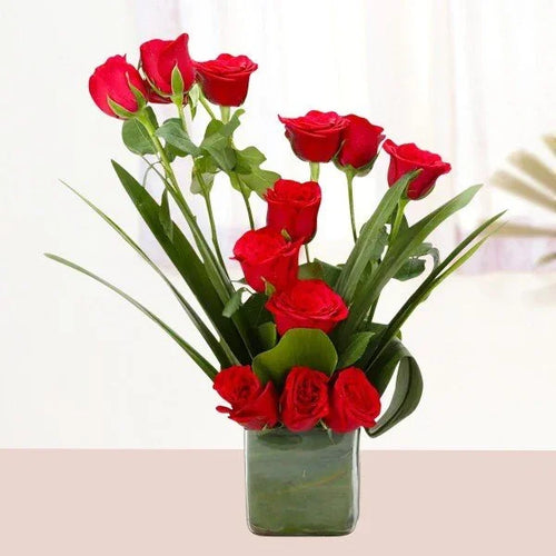 Red rose bouquet in a glass vase with green leaves, ideal for gifting or decoration