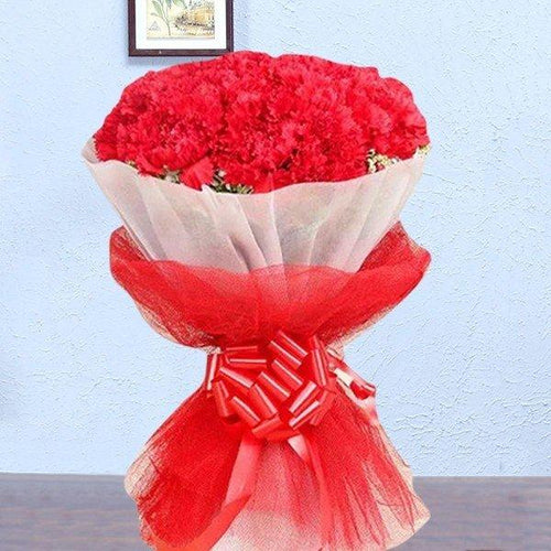 Bouquet of red flowers wrapped in red paper with a decorative bow on a light blue background.