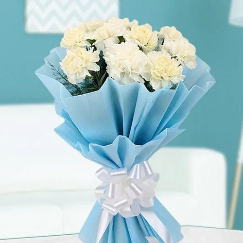 Bouquet of white flowers wrapped in blue paper with a white bow on a light 